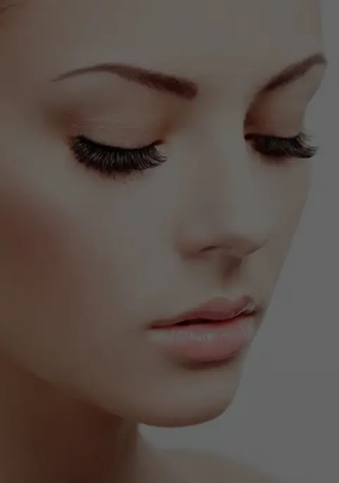 A woman with long eyelashes is looking down.